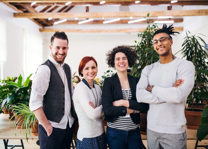 Portrait of group of young businesspeople standing in office, looking at camera.